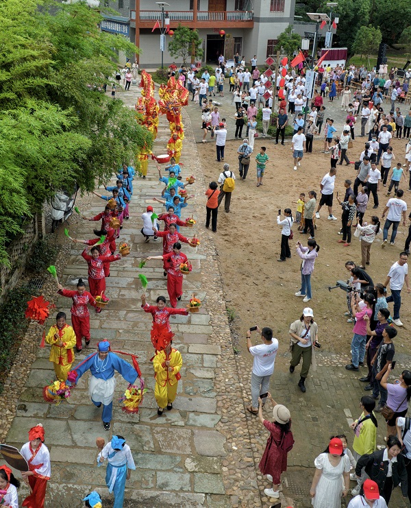 非遗巡游队伍身着传统服饰，吹吹打打进入村子、