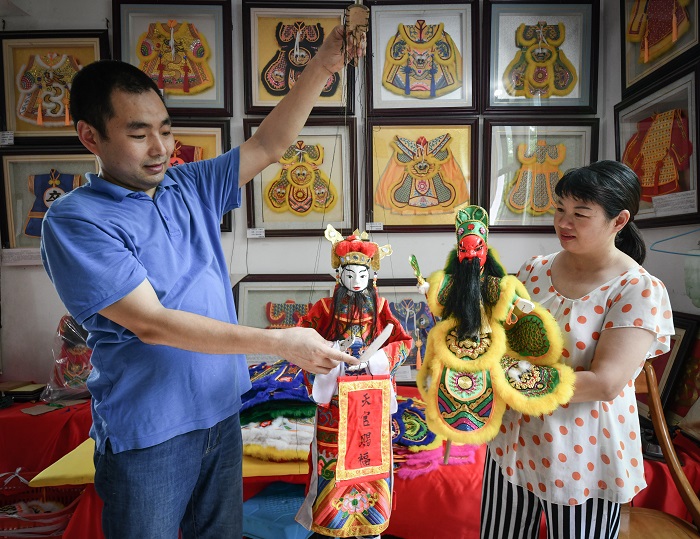 夫妻俩展示的提线木偶戏服等多样性的服饰艺术品