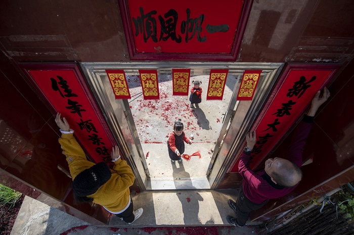 2、2023年1月20日，广西梧州市万秀区夏郢镇古藤村的村民沿袭传统的过年风俗，在自家门头贴春联，喜迎新年。（何华文）