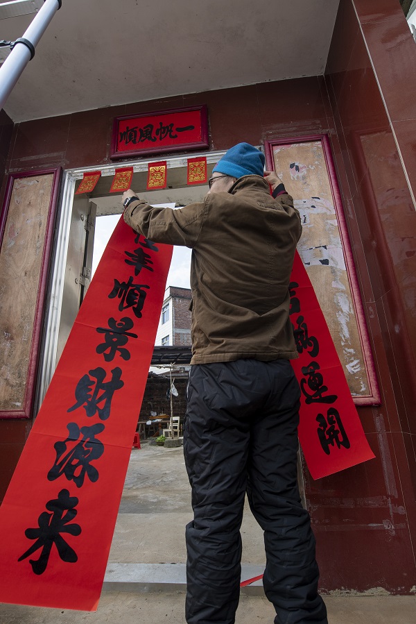 13、2023年1月20日，广西梧州市万秀区夏郢镇古藤村的村民沿袭传统的过年风俗，在自家门头贴春联，喜迎新年。（何华文）