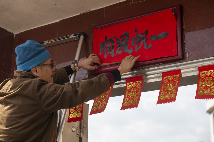 14、2023年1月20日，广西梧州市万秀区夏郢镇古藤村的村民沿袭传统的过年风俗，在自家门头贴春联，喜迎新年。（何华文）