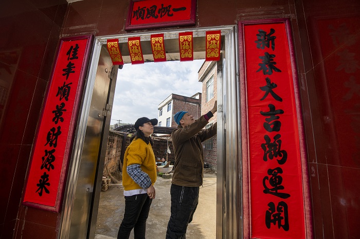 15、2023年1月20日，广西梧州市万秀区夏郢镇古藤村的村民沿袭传统的过年风俗，在自家门头贴春联，喜迎新年。（何华文）