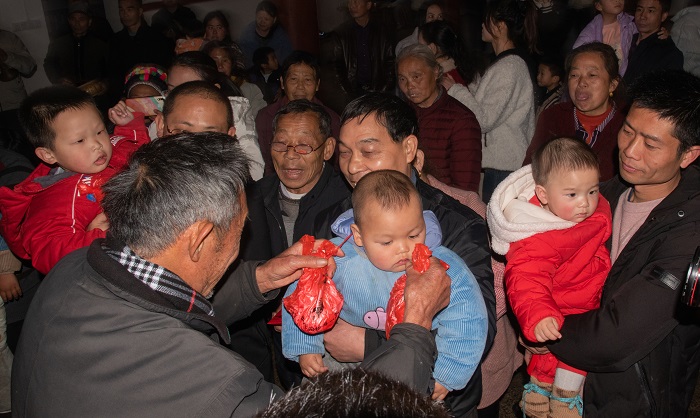 族老把两个鸡腿与红包送给头年出生的孩子，表示添丁祈福。