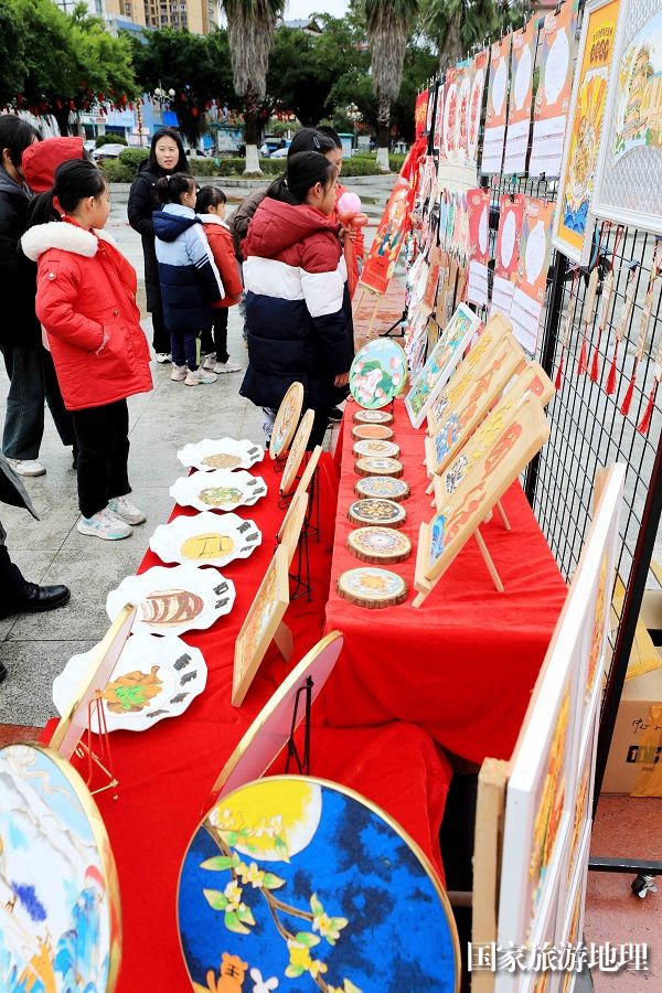 图8：1月20日，在广西柳州市融安县长安广场，学生在非遗集市上选购作品。（谭凯兴 摄）