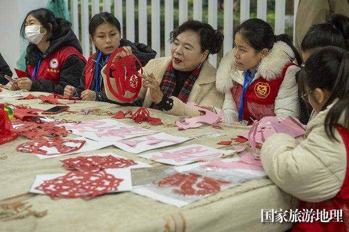 13、2024年1月27日，在广西梧州市万秀区蓝天港湾小区迎春文化活动现场，学生们跟老师学剪窗花。（何华文）