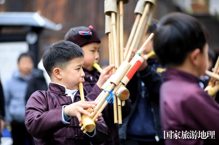 图1：2月2日，一名侗族小朋友在广西柳州市三江侗族自治县林溪镇程阳八寨平寨独柱鼓楼坪上吹奏芦笙。（谭凯兴 摄）