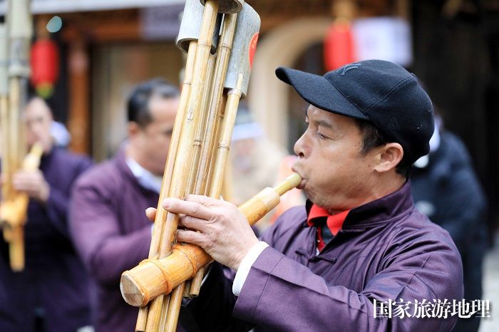 图6：2月2日，一名侗族群众在广西柳州市三江侗族自治县林溪镇程阳八寨平寨独柱鼓楼坪上吹奏芦笙。（谭凯兴 摄）