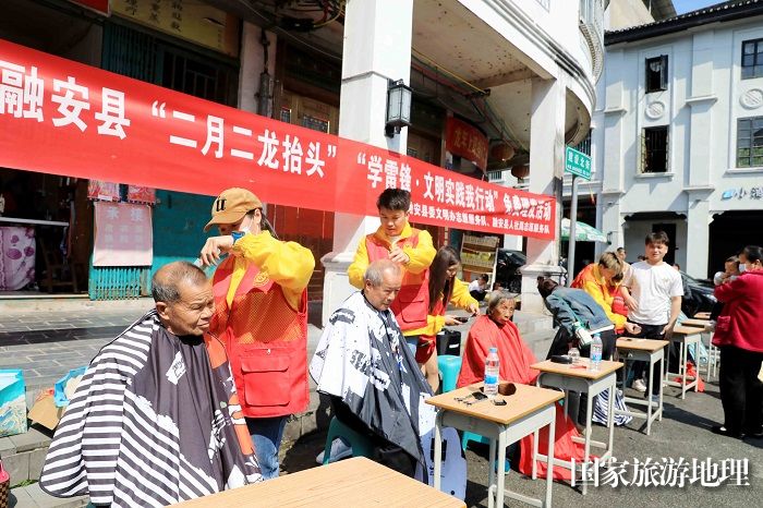 图1：3月11日，在广西柳州市融安县长安镇建设北街，志愿者为市民免费“剃龙头”。（谭凯兴 摄）